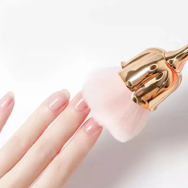 Blume Staubburste rose gold flower brush with soft pink bristles gently dusting manicured nails against white background