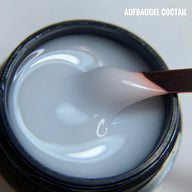 Aufbau Gel Coctail: Milky white builder gel in jar with application spatula showing smooth, creamy texture